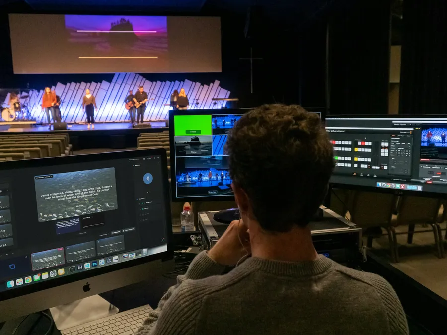A volunteer running Verse Copilot on the church computer, with the band on stage behind
